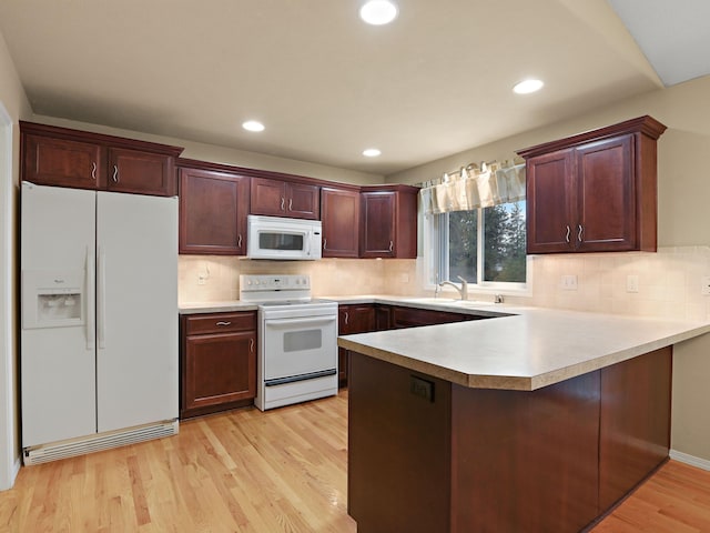 kitchen featuring kitchen peninsula, light hardwood / wood-style flooring, sink, backsplash, and white appliances