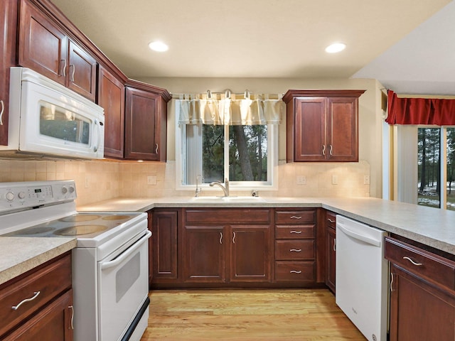 kitchen with light hardwood / wood-style floors, sink, white appliances, and tasteful backsplash