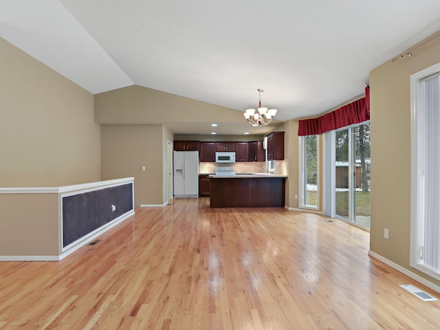 kitchen featuring white appliances, light hardwood / wood-style floors, an inviting chandelier, pendant lighting, and vaulted ceiling