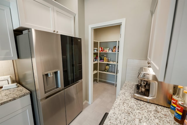 kitchen with white cabinetry, light stone countertops, decorative backsplash, and stainless steel fridge with ice dispenser