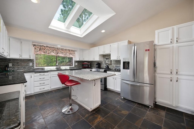 kitchen featuring white cabinets, a kitchen bar, vaulted ceiling with skylight, a center island, and stainless steel appliances