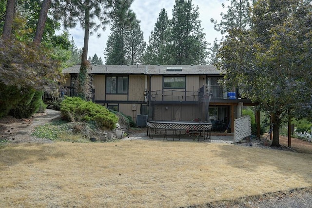 back of property featuring central air condition unit and a yard