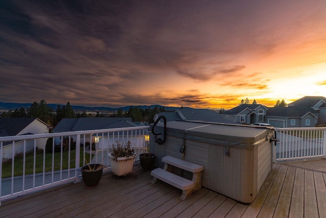 deck at dusk featuring a hot tub