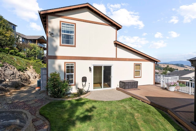 rear view of property featuring a wooden deck and a yard