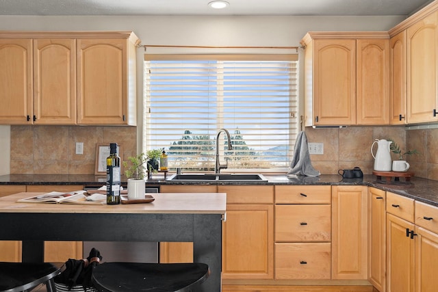 kitchen with sink, dark stone countertops, light brown cabinetry, and decorative backsplash