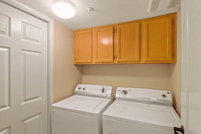 clothes washing area with cabinets and separate washer and dryer