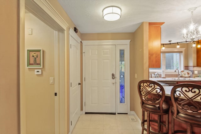 entrance foyer featuring sink, an inviting chandelier, a textured ceiling, and light tile patterned floors