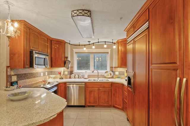 kitchen with stainless steel appliances, tasteful backsplash, sink, and decorative light fixtures