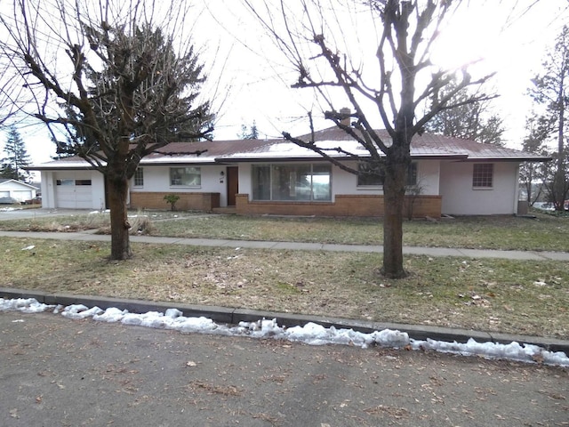 ranch-style house featuring a garage and a front lawn