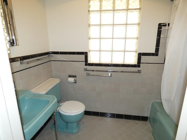 full bathroom with tile patterned floors, toilet, sink, tile walls, and shower / bath combination with curtain