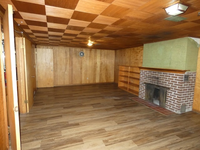 interior space with hardwood / wood-style flooring, a brick fireplace, wooden ceiling, and wood walls