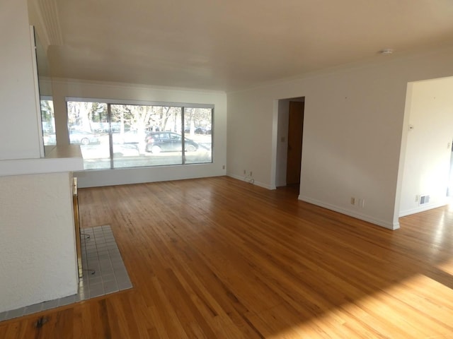 unfurnished living room featuring crown molding and hardwood / wood-style floors