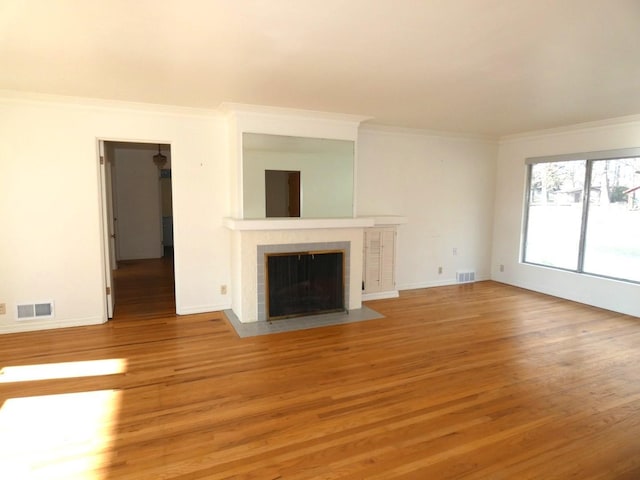 unfurnished living room with hardwood / wood-style flooring, a tile fireplace, and ornamental molding