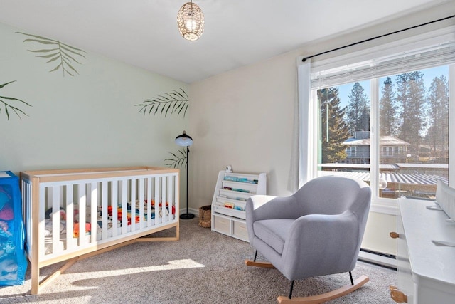 bedroom with a nursery area, carpet, and a baseboard heating unit