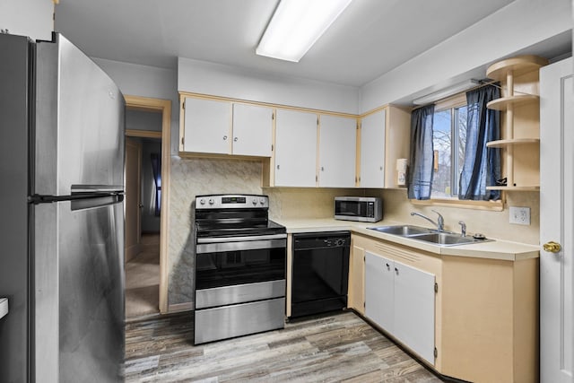 kitchen featuring sink, white cabinetry, stainless steel appliances, light hardwood / wood-style floors, and decorative backsplash