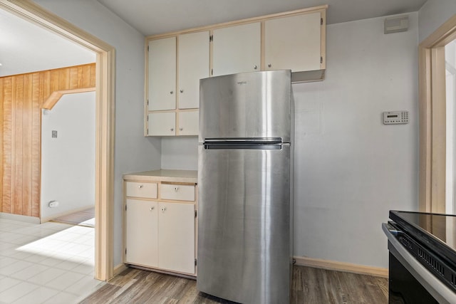 kitchen featuring wooden walls, stainless steel fridge, light hardwood / wood-style floors, and cream cabinetry