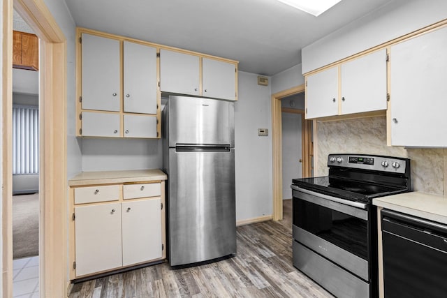 kitchen with decorative backsplash, appliances with stainless steel finishes, white cabinets, and light hardwood / wood-style flooring