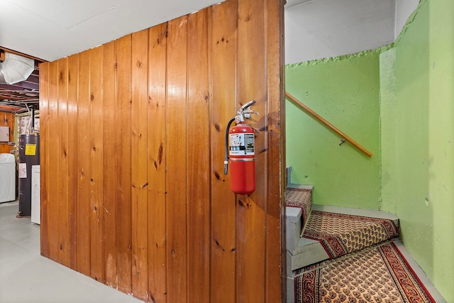 interior space with wooden walls, washer / dryer, and water heater