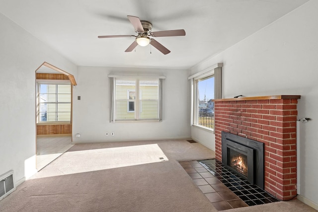 unfurnished living room featuring a brick fireplace, ceiling fan, and carpet flooring