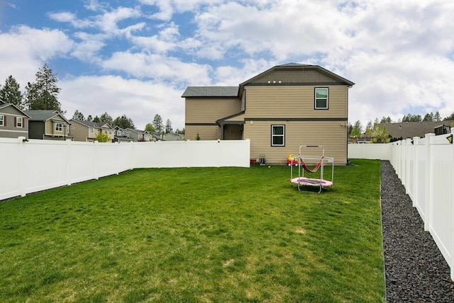 rear view of property with a yard, a residential view, and a fenced backyard