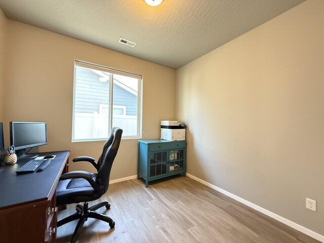 home office featuring light hardwood / wood-style flooring and a textured ceiling