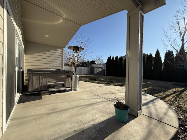 view of patio with a hot tub and a storage shed