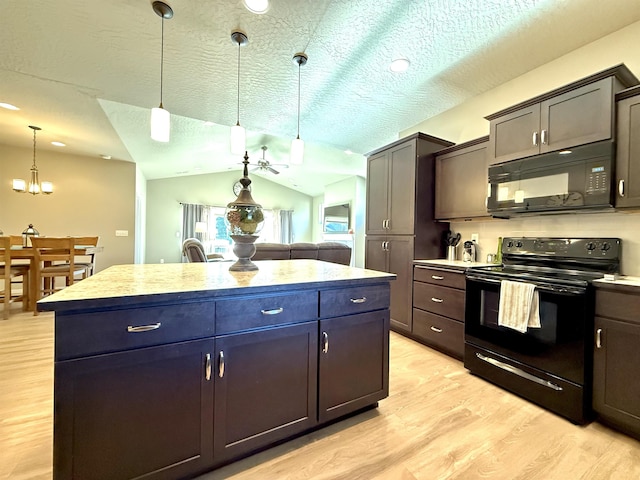 kitchen featuring lofted ceiling, decorative light fixtures, light wood-type flooring, a kitchen island, and black appliances