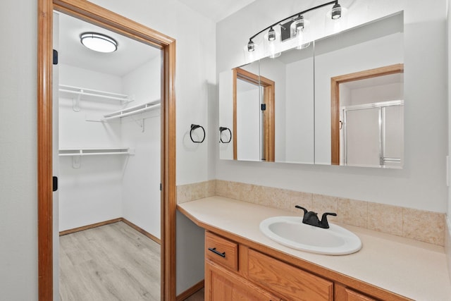 bathroom featuring hardwood / wood-style flooring, vanity, and a shower with shower door