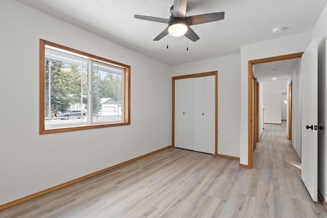 unfurnished bedroom featuring ceiling fan, light hardwood / wood-style floors, a closet, and a textured ceiling