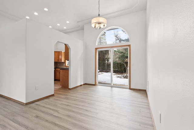 interior space with light hardwood / wood-style floors, a chandelier, and a high ceiling