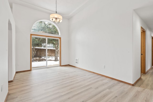 interior space with a towering ceiling, light wood-type flooring, and a notable chandelier