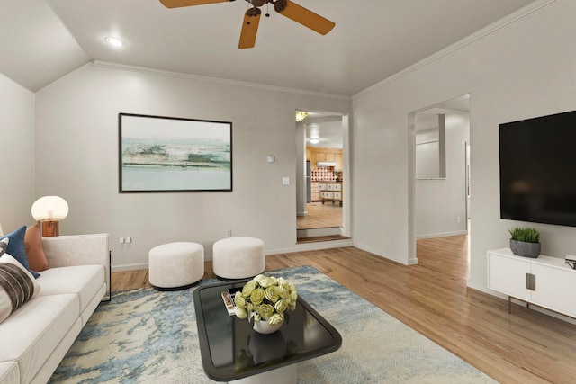 living room with lofted ceiling, light hardwood / wood-style flooring, ornamental molding, and ceiling fan