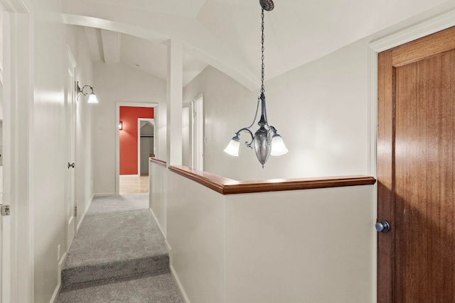 corridor with lofted ceiling with beams, carpet floors, and a notable chandelier