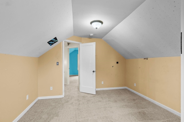 bonus room with lofted ceiling and light carpet