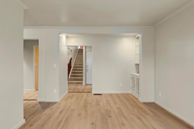 empty room with crown molding and light wood-type flooring