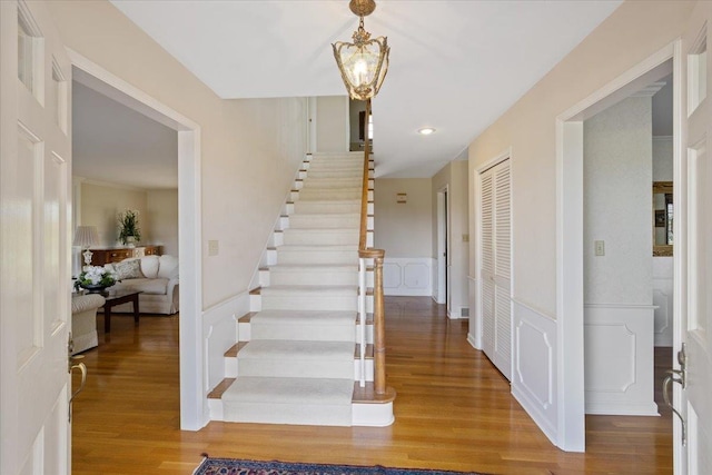 stairway with an inviting chandelier and hardwood / wood-style flooring