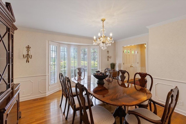 dining area with a notable chandelier, ornamental molding, and light wood-type flooring