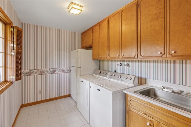 clothes washing area featuring separate washer and dryer, sink, light tile patterned floors, and cabinets