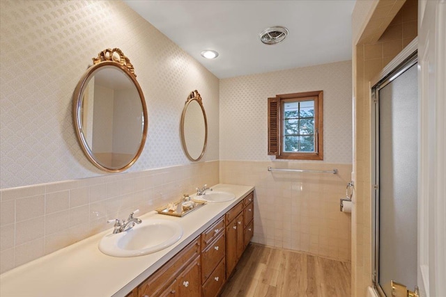 bathroom featuring hardwood / wood-style floors, a shower with door, and tile walls