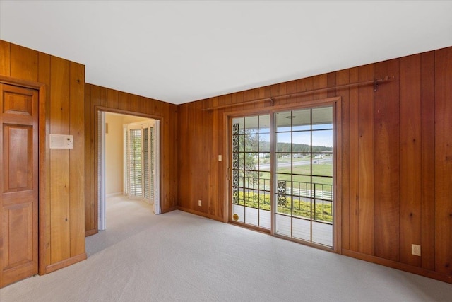 unfurnished room with light carpet and wood walls