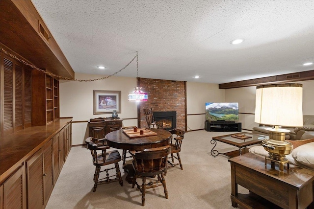 dining room with light colored carpet, a fireplace, and a textured ceiling