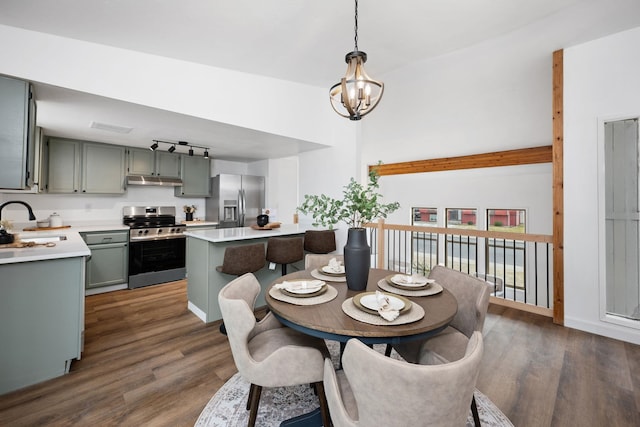 dining space with dark wood-type flooring, sink, and an inviting chandelier