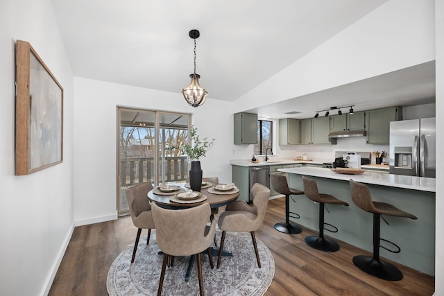 dining space with lofted ceiling, sink, a notable chandelier, and dark hardwood / wood-style floors