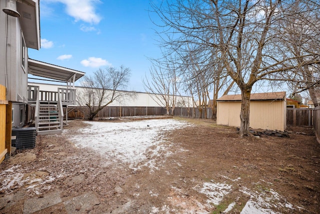 yard covered in snow featuring a shed and cooling unit