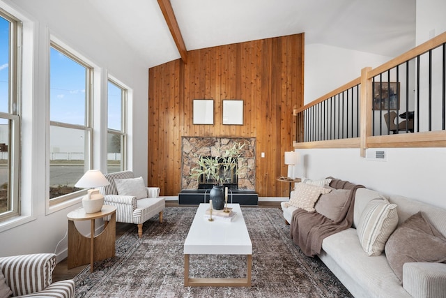 living room featuring lofted ceiling with beams, a healthy amount of sunlight, and wooden walls