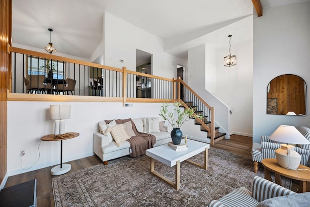 living room with dark wood-type flooring, a chandelier, and lofted ceiling with beams