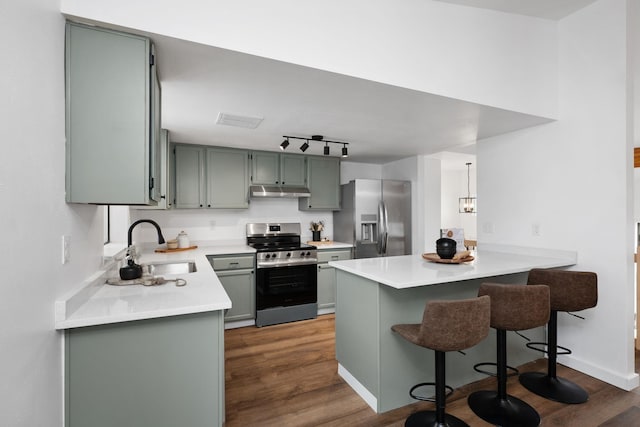 kitchen featuring dark wood-type flooring, stainless steel appliances, kitchen peninsula, and sink