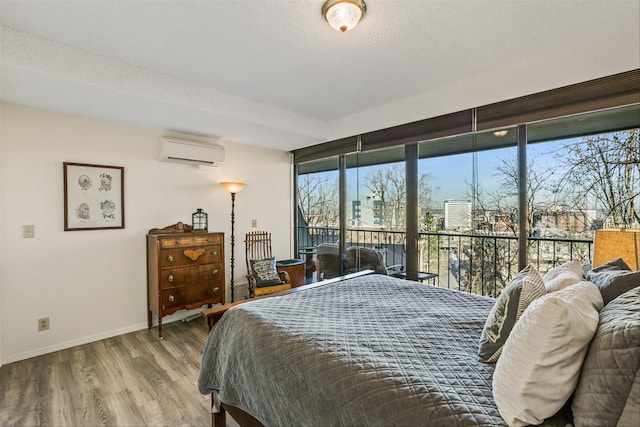 bedroom with hardwood / wood-style flooring, a textured ceiling, and a wall unit AC