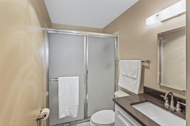 bathroom featuring vanity, a shower with shower door, and toilet