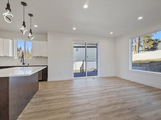 kitchen featuring sink, white cabinetry, decorative light fixtures, a kitchen island, and decorative backsplash